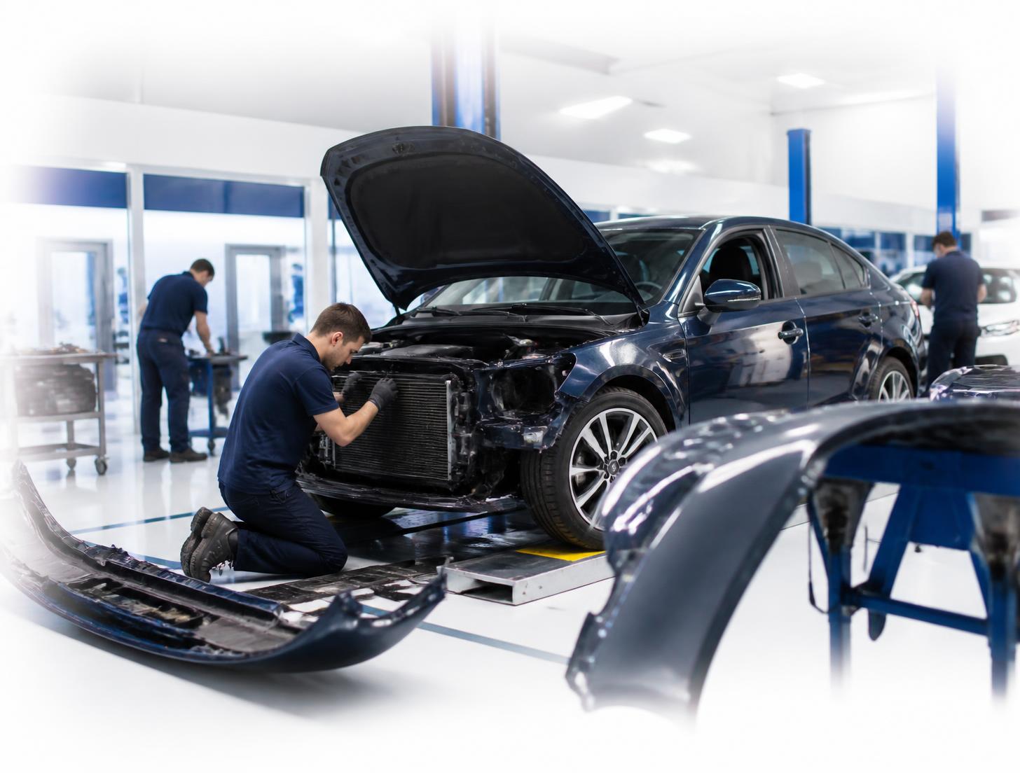 Technicians repairing an accident damaged car inside a modern bodyshop